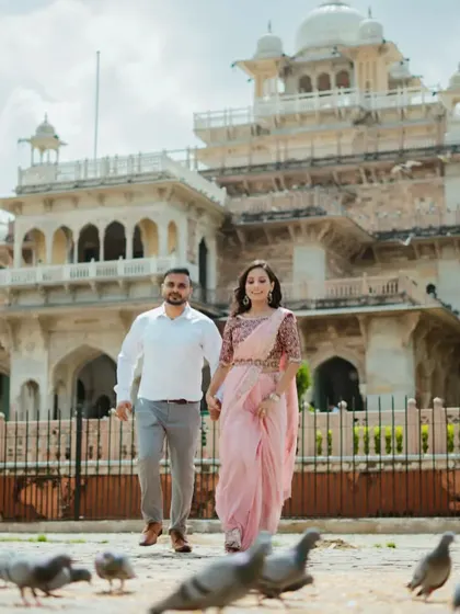 A confident walking shot towards the camera, with Albert Hall and the famous pigeons creating a classic Jaipur scene. This photo is full of style and energy.