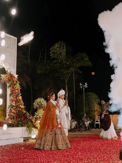The couple on stage during their Varmala, framed by smoke and sparklers. This adds a dramatic and celebratory feel to the ceremony photos.
