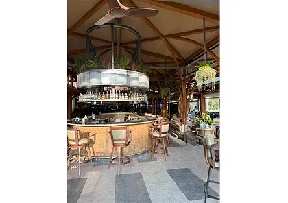 Another perspective of the circular bar, where hanging ferns and integrated planters soften the industrial-chic design. This balance of materials is key to creating a space that feels both modern and timeless.