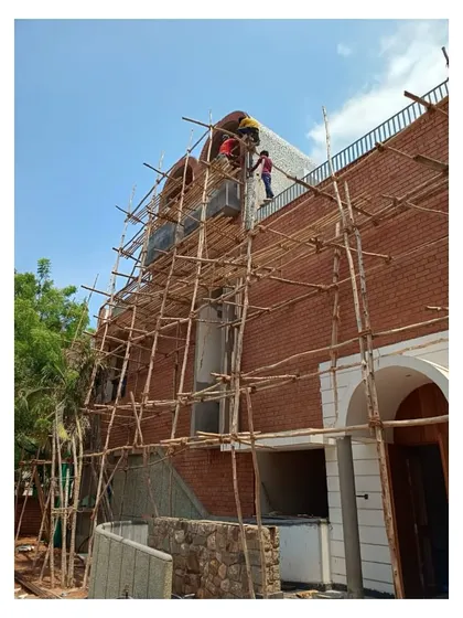 The exterior of the Brick Vault House nearing completion, with workers on scaffolding putting the finishing touches on the brick cladding. This phase is about fine-tuning the details before handing the building over to its inhabitants.