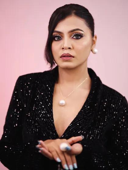 This pose highlights the contrast between the sharp makeup and the soft pearl accessories. It’s all about creating a balanced and interesting look.
