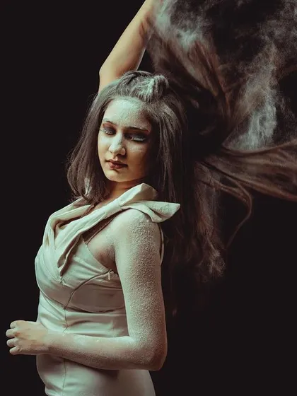 An experimental studio portrait using powder to create texture and movement. The model tosses her hair, and the exploding powder freezes in a cloud around her, resulting in a dynamic and abstract image.