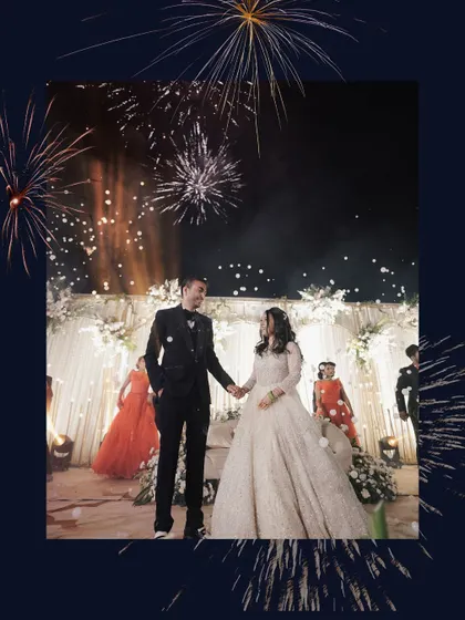 A romantic shot of the couple on stage, framed by fireworks, capturing the grand finale of their Sangeet performance.