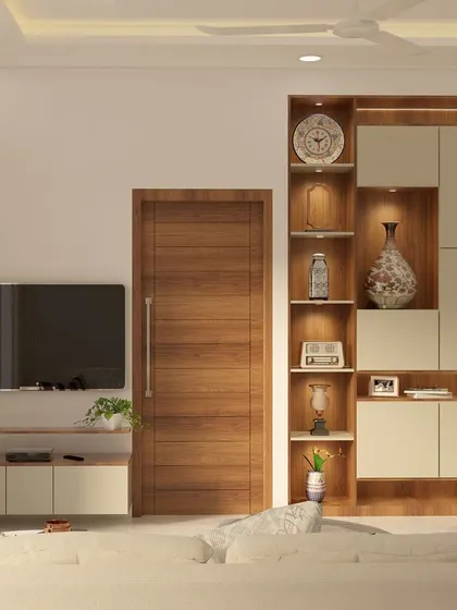 A full view of the living room from the Yelahanka project, showcasing the TV unit, display cabinet, and neutral-toned sofa. The design is clean, modern, and functional.