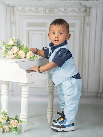 A star in the making, playing tunes of pure magic. This little boy looks sharp in his vest and trousers as he stands at the miniature piano.
