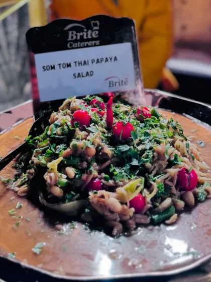 A close-up of the freshly made Som Tom Thai Papaya Salad, garnished with cherry tomatoes and herbs.
