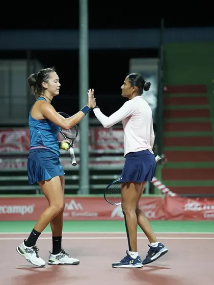 A high-five between doubles partners, reinforcing teamwork and morale during a match.