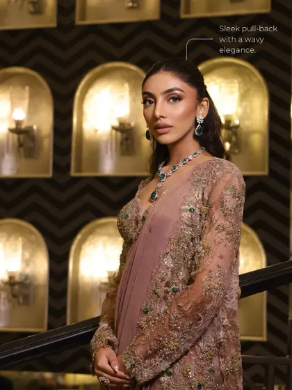 The sleek pullback hairstyle with wavy elegance perfectly complements the 'Golden Glaze' makeup, creating a polished and modern silhouette.