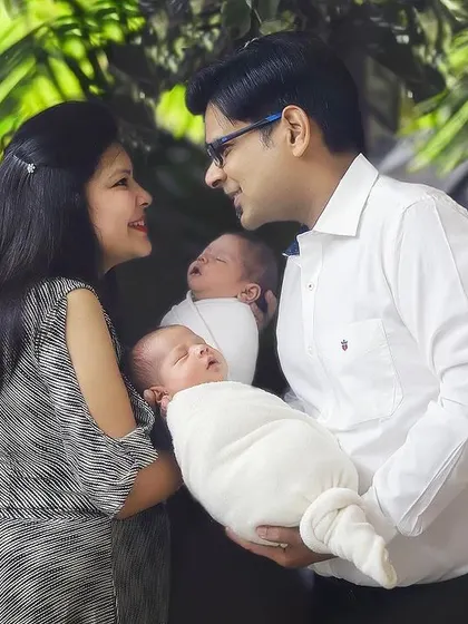 Twice the smiles, twice the love. A beautiful candid moment between new parents as they gaze lovingly at each other while holding their precious newborn twins.