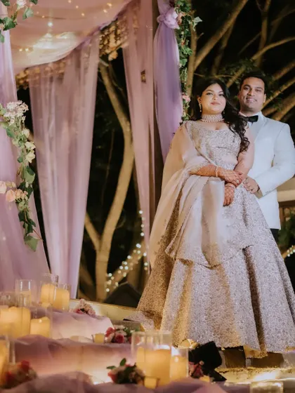 A portrait of elegance. The couple poses under a canopy of soft lavender drapes and a crystal chandelier, a romantic and dreamy setting we created for their cocktail party.