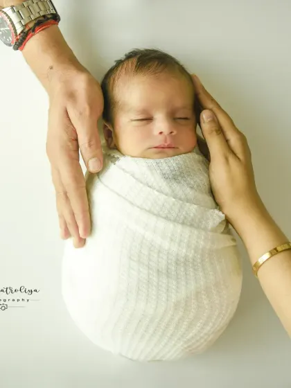 Parents' hands gently cradling their baby's head. This close-up shot emphasizes the delicacy of a newborn and the protective love of their family.