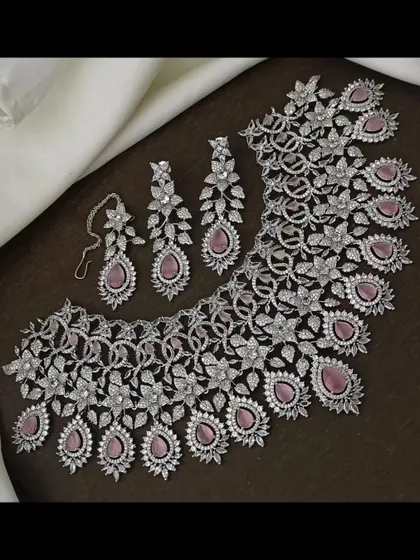 This intricate CZ stone necklace set with pink stones is a beautiful choice for a reception. The floral and leaf motifs give it a delicate look.