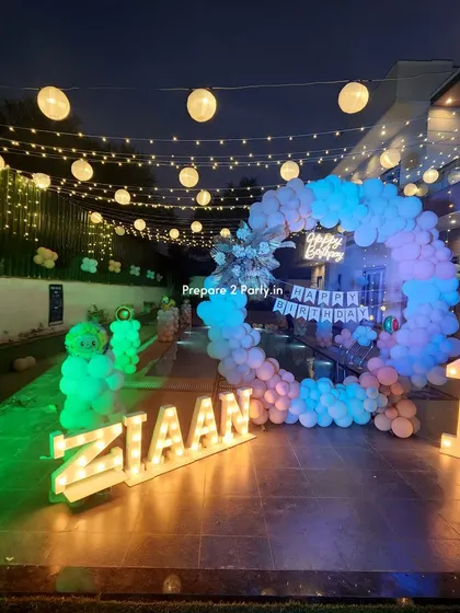 The "ZIAAN" first birthday poolside setup viewed from a different angle, highlighting the glowing marquee letters and the reflection of the lights on the patio.