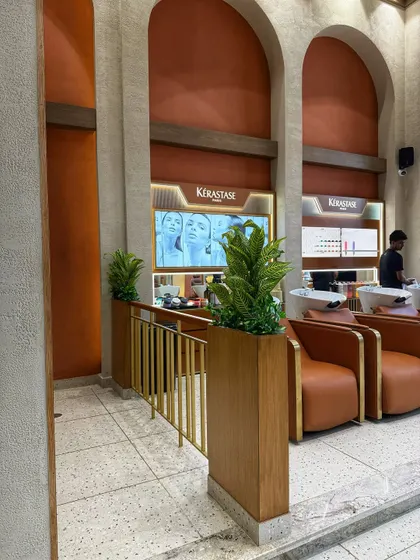 Tall wooden planters with artificial plants serve as elegant dividers and add a touch of nature to the entrance of Looks Salon. This is a great way to guide foot traffic while enhancing the decor.