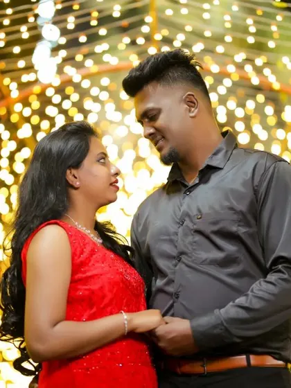 A close-up shot within a tunnel of lights, focusing on the couple's interaction. The warm, sparkling lights create a festive and intimate mood.