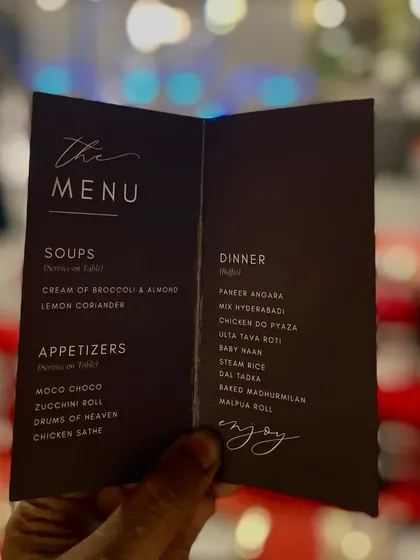 A hand holds up a simple yet elegant menu for a reception dinner. The clear, classic font and layout make it easy for guests to see the delicious options available.
