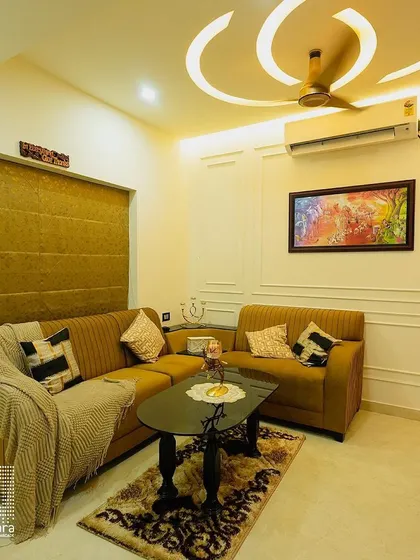 Comfort is key in this cozy living space, featuring a plush brown sectional sofa and a custom-designed ceiling with recessed lighting. The Roman blinds offer a clean, tailored look for the windows.