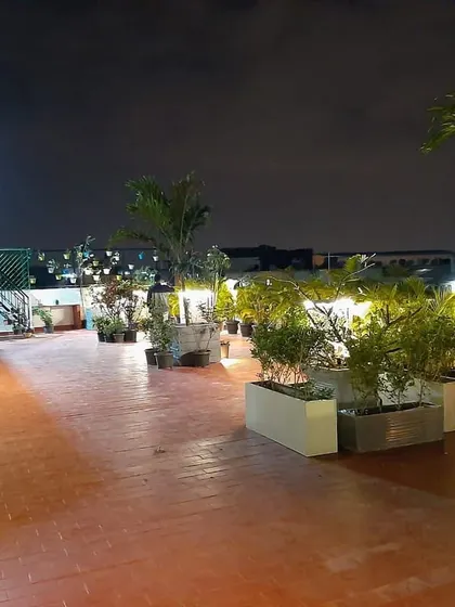 A 1500 sqft commercial terrace garden I designed on Kanakpura Road, pictured at night. The layout uses large planters to define the space and incorporates strategic garden lighting to create a warm and inviting ambiance for evening use.