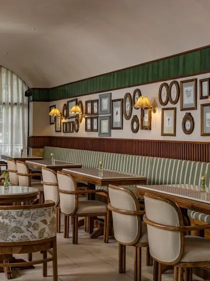 The cafe's interior features a gallery wall of framed pictures and custom upholstery, adding a personal and curated touch to the space.
