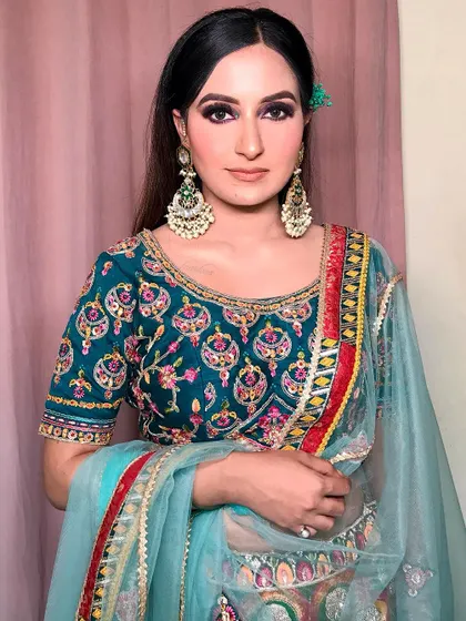 A full portrait showcasing the complete look. The teal and multi-color outfit is vibrant and fun, and the bold eye makeup is the perfect choice to match its energy.