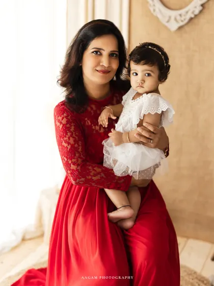 A beautiful mother-daughter portrait in a lifestyle setting. The mother's red lace dress and the soft natural light create an elegant yet relaxed image.