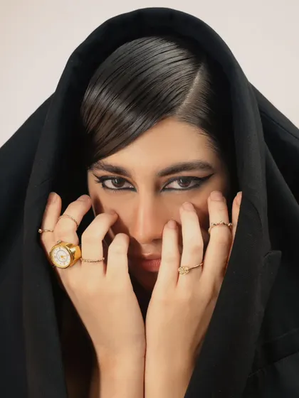 An intense close-up that creates a sense of mystery and intrigue. The focus is on the eyes and the sleek, graphic makeup.