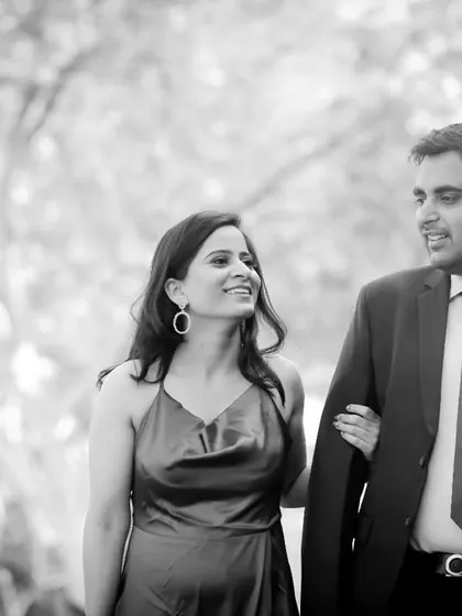 A classic black and white walking portrait from a pre-wedding shoot. The soft, natural light and the couple's gentle smiles create a timeless and elegant photograph.