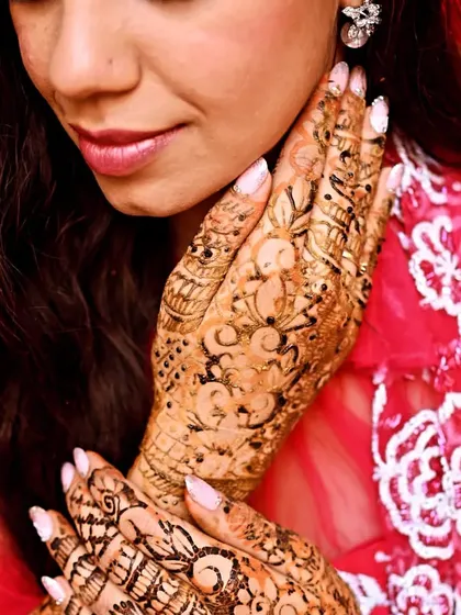 A close-up, artistic shot of a bride's face and her detailed mehandi.