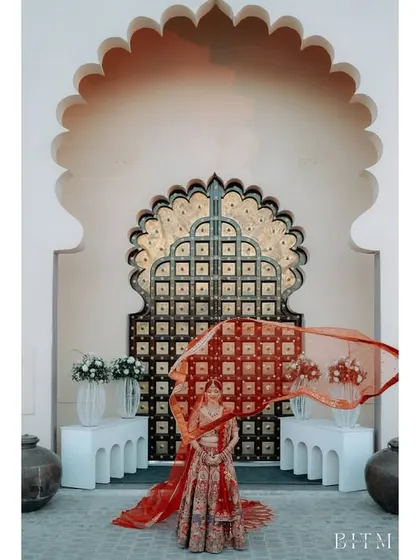 A bride twirls, her red veil flying in the air against a beautifully detailed palace door. This shot is full of movement, grace, and royal elegance.