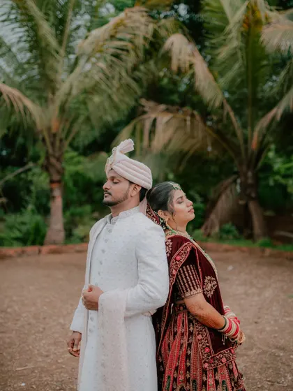 An artistic back-to-back pose, showcasing the couple's elegant reception outfits against a natural backdrop.