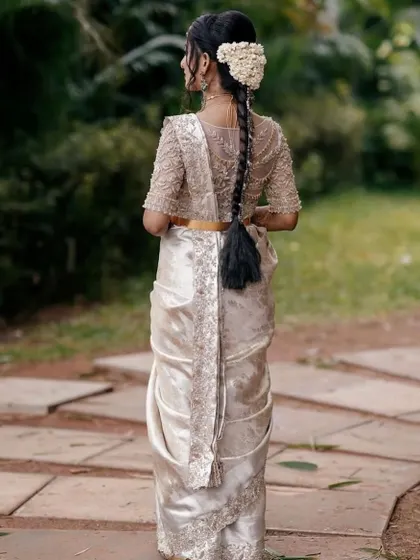 A beautiful back view of the bride's ensemble. The intricate embroidery on the blouse and the traditional braided hairstyle create a look of timeless elegance.