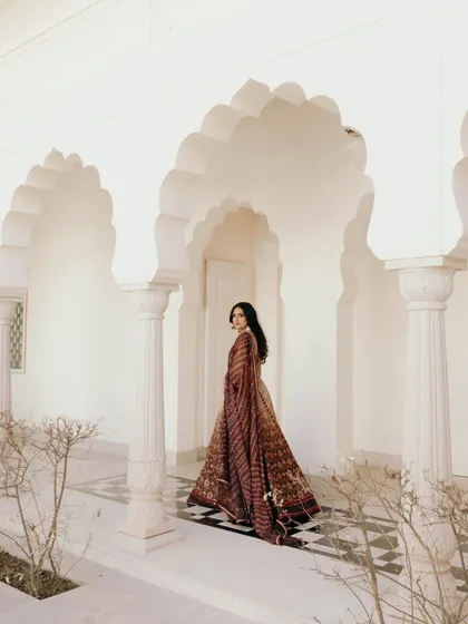 A graceful portrait of Sandy walking through a corridor at the Oberoi Sukhvilas. The play of light and shadow, along with the architectural arches, creates a beautiful composition.