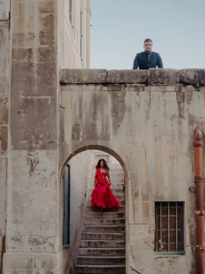 A dramatic portrait using the historic architecture of Malta to frame the couple, with the bride descending a stone staircase towards the groom.