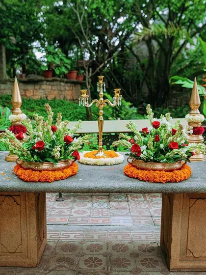 A close-up of the traditional floral arrangements, featuring red roses and tuberoses in brass vessels, adding a touch of classic elegance to the Haldi decor.