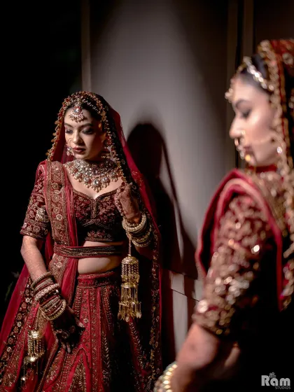 A stunning close-up of the bride looking in the mirror, her reflection perfectly captured. The dramatic lighting highlights her beautiful features and intricate jewelry.