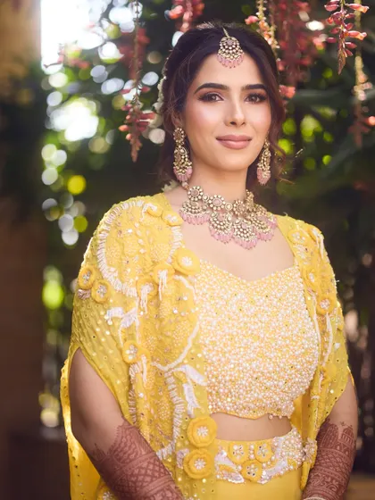A portrait of our radiant Haldi bride. The makeup is kept soft and glowing, with a focus on flawless skin and subtly defined eyes to balance her bright yellow outfit.