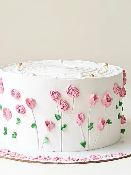 A simple white cake adorned with delicate pink buttercream tulips. This minimalist design focuses on clean lines and the beauty of hand-piped floral art.