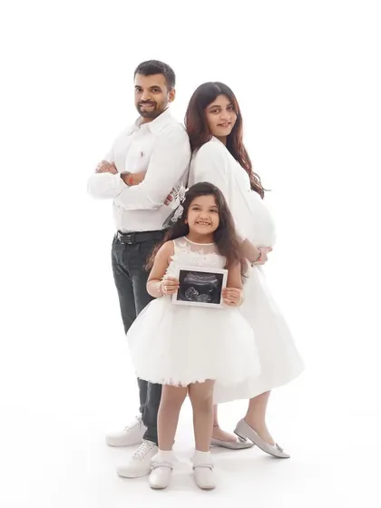 A beautiful family maternity portrait where the big sister-to-be proudly holds up the ultrasound photo, announcing the new arrival.