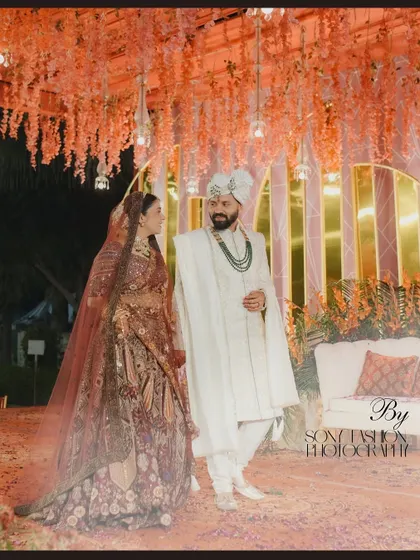 A beautiful portrait of a couple under a canopy of orange flowers, their gazes locked, capturing a moment of deep connection.