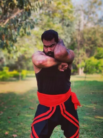 A demonstration of a powerful blocking technique from the Kalaripayattu system. This pose shows the immense upper body strength and control required to master this ancient martial art.