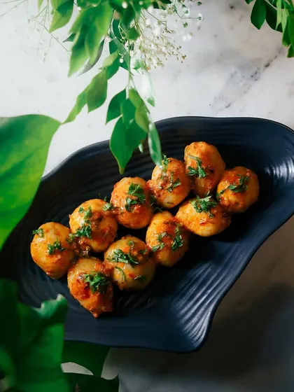 A different view of the Honey Tamarind Potatoes, showcasing the glossy sauce and fresh garnish. This is a standout vegetarian dish for any event.