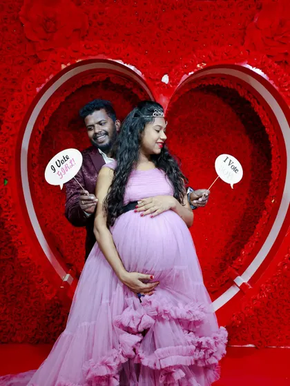 A fun maternity shoot with props. The couple holds up signs for a "gender reveal" vote while posing in our heart-shaped studio prop.