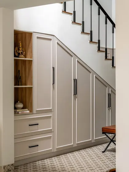 We believe in maximizing every inch of space. Here, the area under the stairs was converted into elegant, paneled storage cabinets, blending seamlessly with the home's classic aesthetic while providing essential functionality.