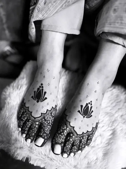 A minimalist and elegant feet mehandi design. This black and white photo highlights the simple yet beautiful lotus motifs, perfect for a modern bride.