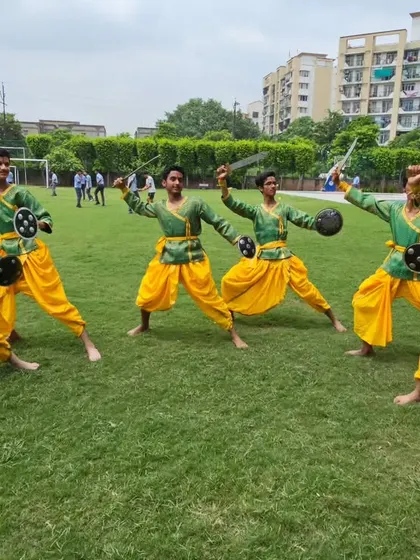 My young students practicing their Chhau routine outdoors on the grass, holding swords and shields.