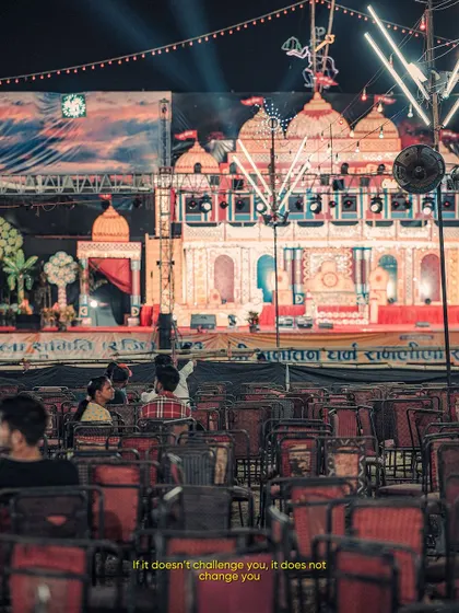A shot from a local mela (fair) at night. The empty chairs in front of the brightly lit stage create a sense of anticipation and tell a story about the moments before a performance.
