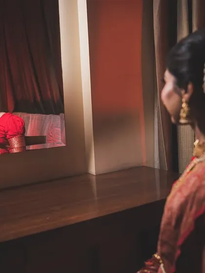A creative reflection shot of the bride, Pragya, as she gets ready, capturing a moment of quiet introspection.