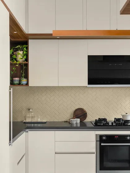 The 'Poorna' kitchen is treated in subtle, muted tones, with a herringbone tile backsplash adding a fresh, textural dimension.