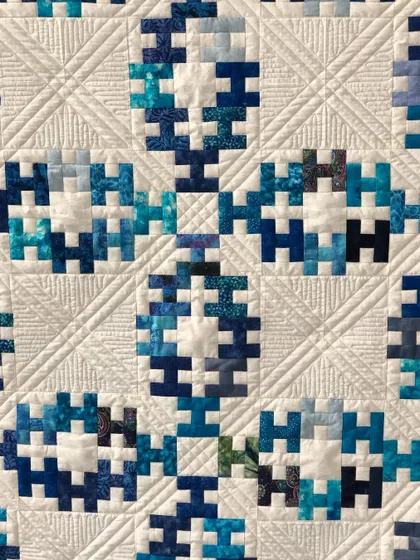 A close-up of a "Summer Wedding Ring" quilt, showing the intricate ruler work.