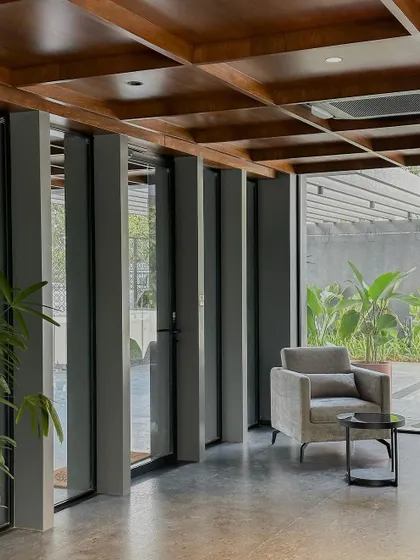 A secondary seating area with a view of the exterior landscaping. Full-height glass walls and operable vertical louvers allow for control over light and privacy, seamlessly connecting the interior with the outdoors.